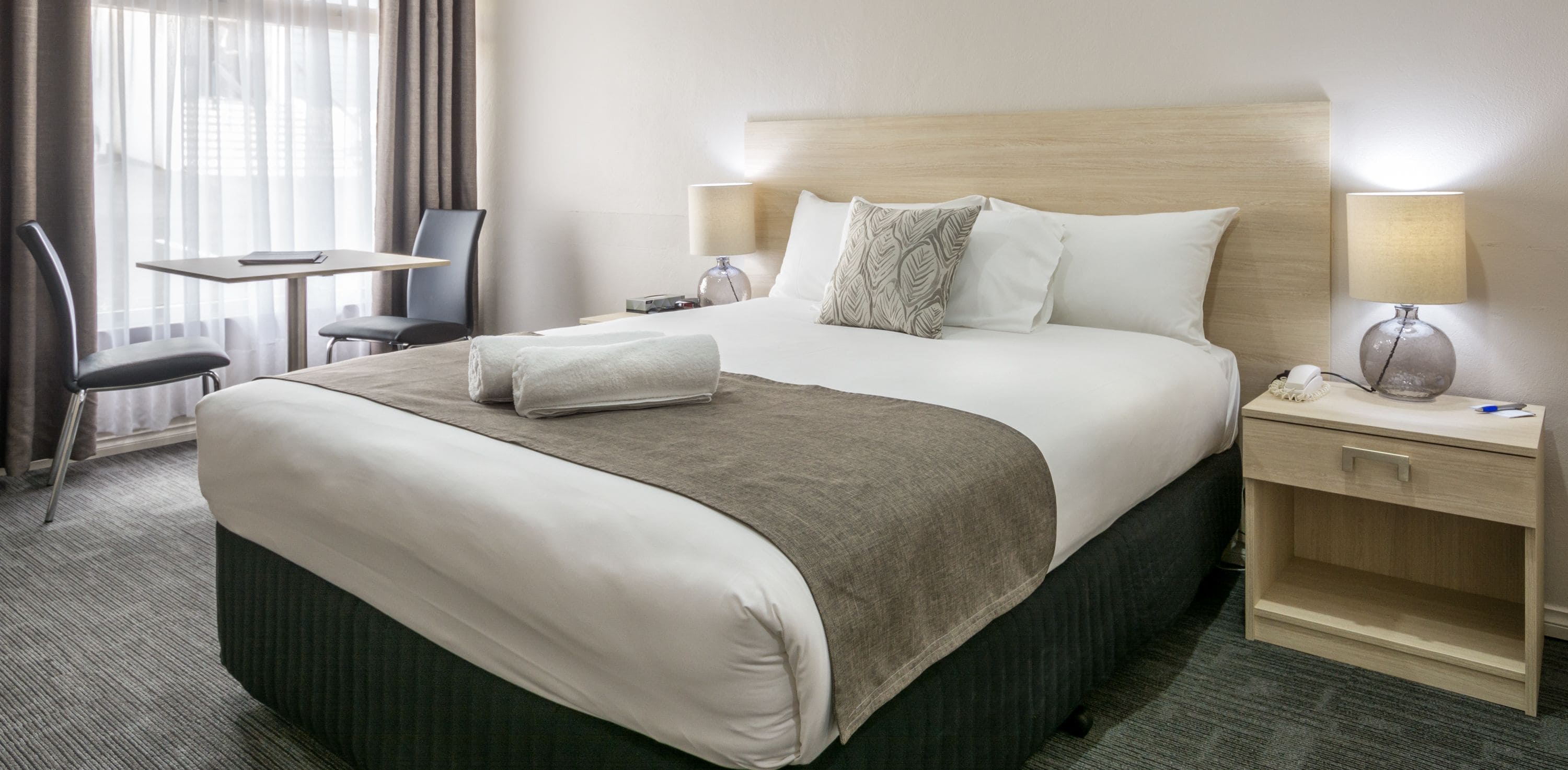 Een hotelkamer met een groot bed, een bureau, een stoel en een lamp.