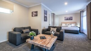 A hotel room with a bed, two sofas, a coffee table, and a potted plant. - Mandala Ace Albany Hotel (Centennial Park)