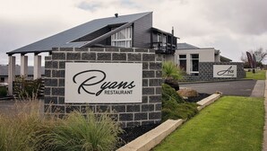 A Ryans Restaurant sign with a stone facade, a modern building in the background, and a well-maintained lawn. - Mandala Ace Albany Hotel (Centennial Park)