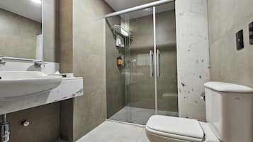 Un baño moderno con ducha acristalada, lavamanos blanco y retrete.