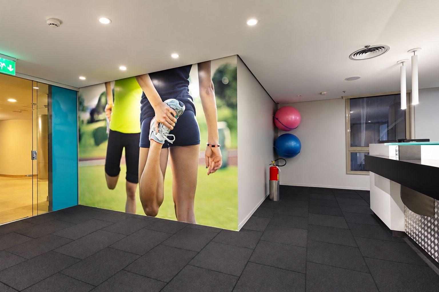 A modern reception area with a large wall mural, a reception desk, and exercise balls.