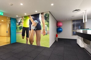 Ein moderner Empfangsbereich mit einer großen Wandmalerei, einem Empfandtisch und Gymnastikbällen.
