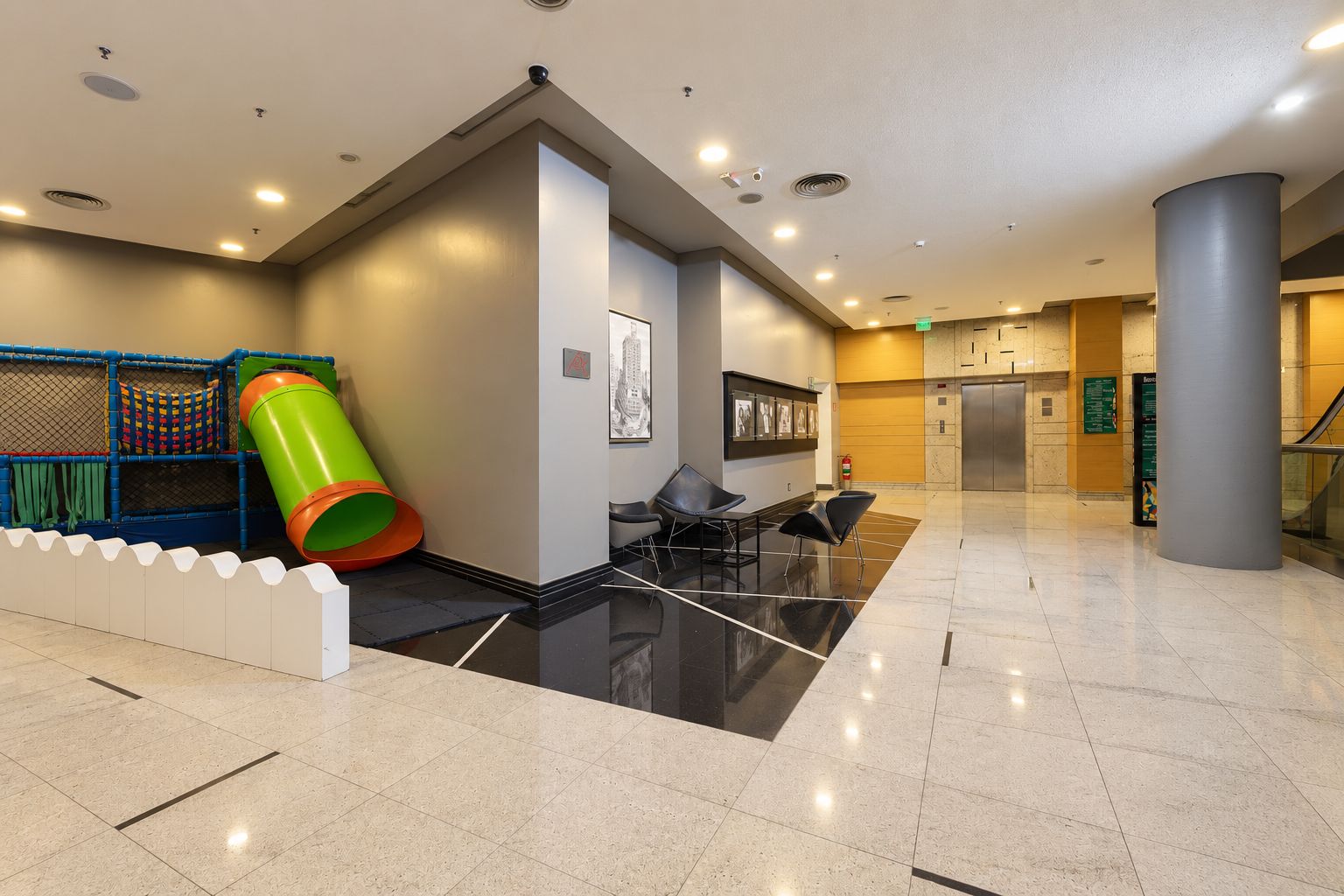 Un hall d ’entrée moderne doté d’un espace de jeux, de sièges et d’un ascenseur.