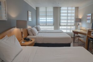 Ein Hotelzimmer mit zwei Betten, einem Schreibtisch, einem Stuhl, einer Lampe und einem Fernseher.