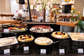 Un buffet proposant une variété de desserts et de boissons, notamment des gâteaux, des tartes et des fruits.