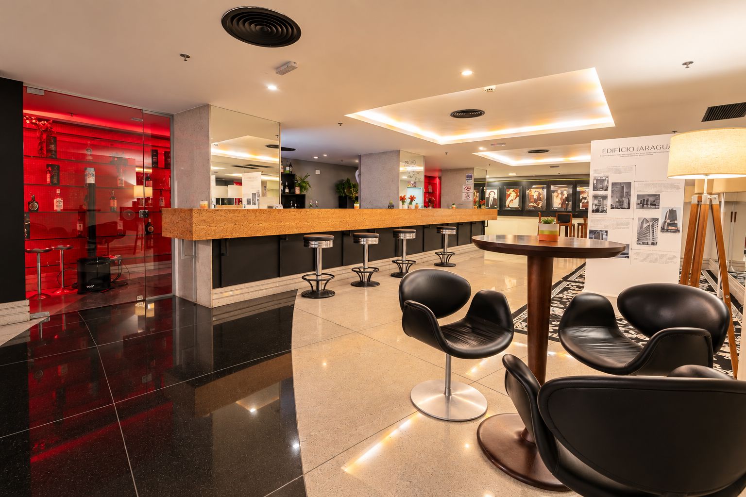 Un hall d’hôtel moderne comprenant un comptoir d’accueil, un bar et un espace détente avec des sièges.