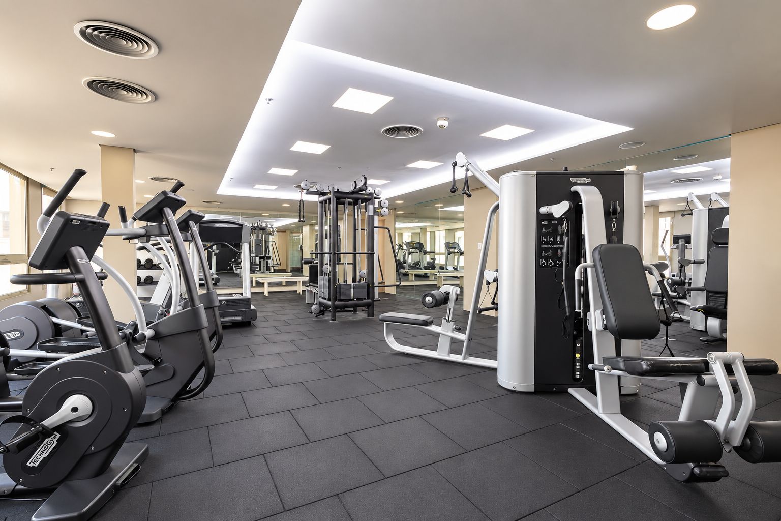 A gym with various exercise equipment, including treadmills, weight machines, and free weights.