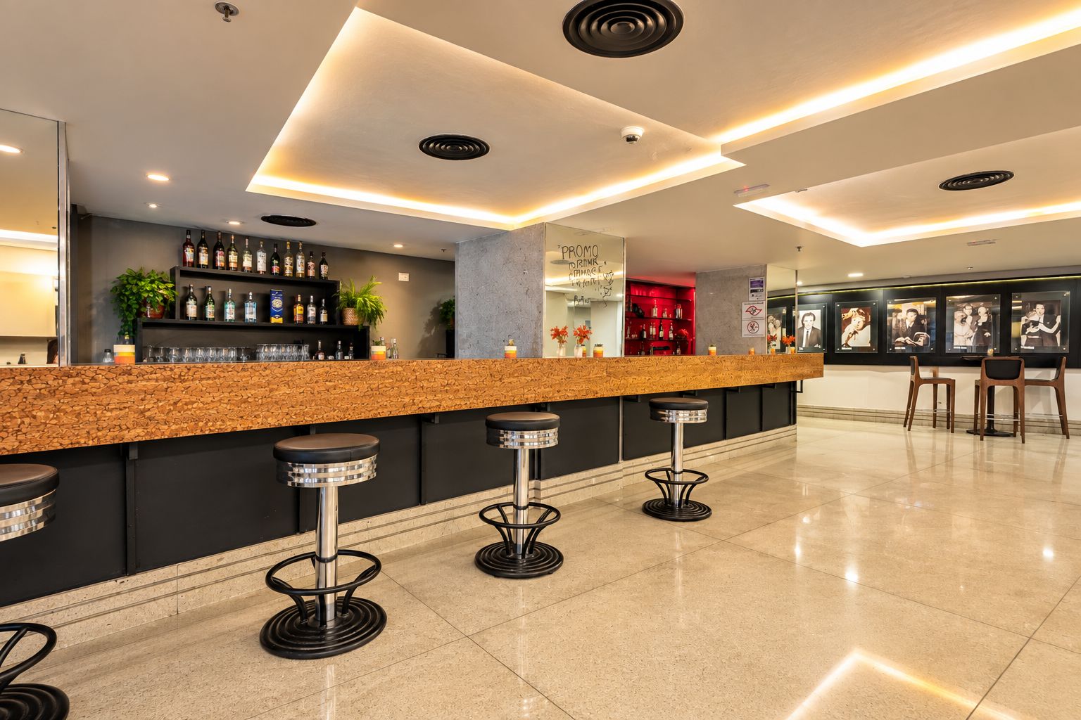 A modern bar area with a stone counter, bar stools, and a selection of bottles.