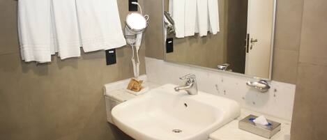 Une salle de bain avec un lavabo blanc, un miroir et plusieurs serviettes blanches suspendues à un porte-serviettes.