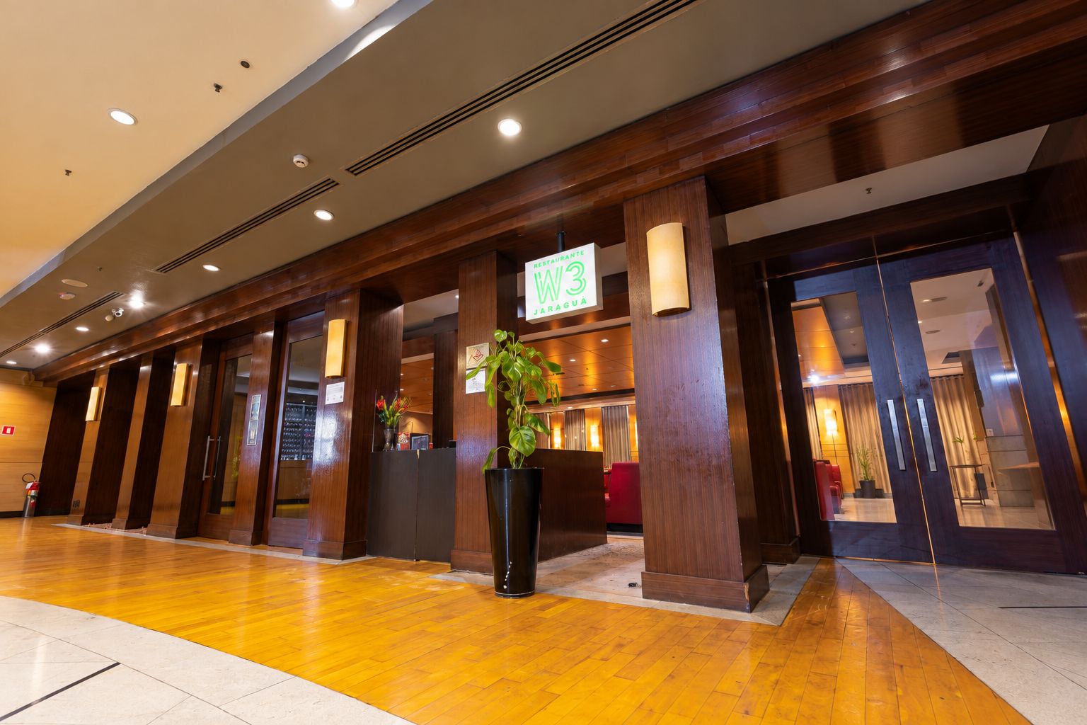 A hotel lobby with a reception desk, a sign for 'RESTAURANT TE PARAGUA,' and a potted plant.