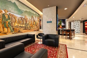 Eine Lobby mit einer großen Wandmalerei, einem Empfangsbereich und einer Sitzecke.