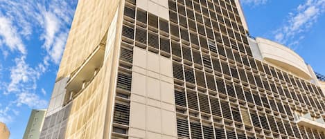 Un hôtel moderne, avec une façade à motifs géométriques, une entrée imposante et une enseigne indiquant qu’il s’agit d’un hôtel.