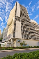 A modern hotel building with a grid-like facade, a prominent entrance, and a sign indicating it is a hotel.
