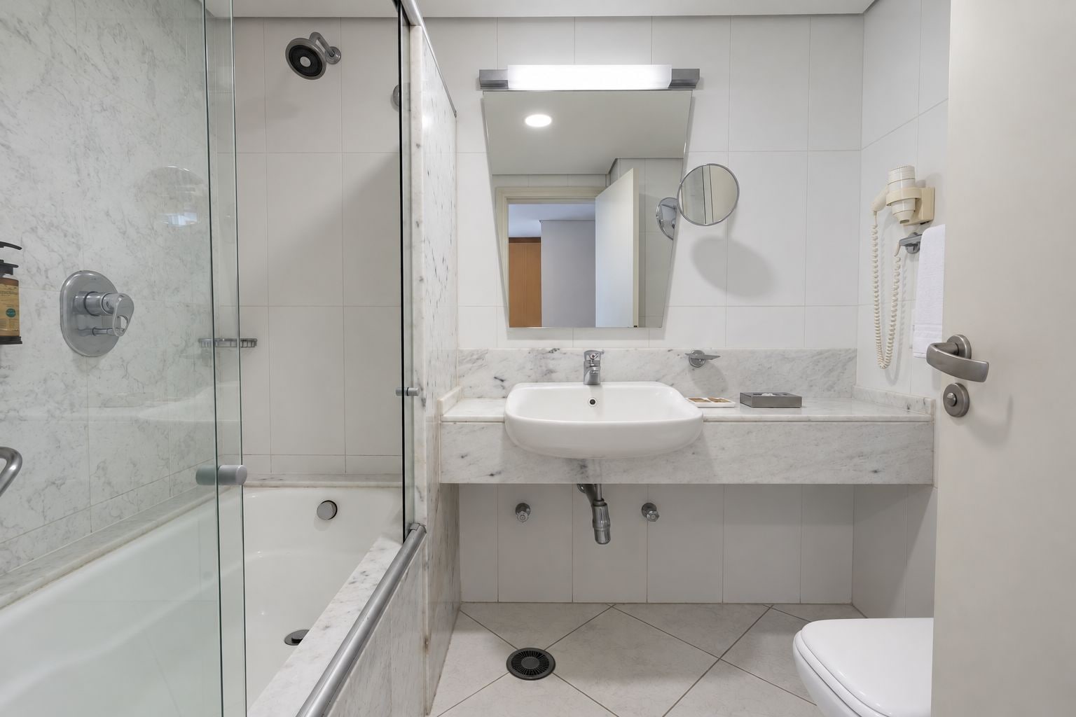 Un baño moderno con ducha envuelta en vidrio, un lavamanos blanco y un inodoro.