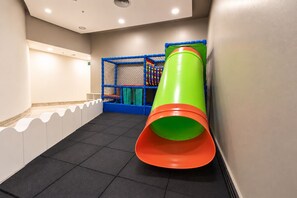 A play area with a slide, padded flooring, and a netted play structure. - Hotel Nacional Inn Jaraguá São Paulo (São Paulo)