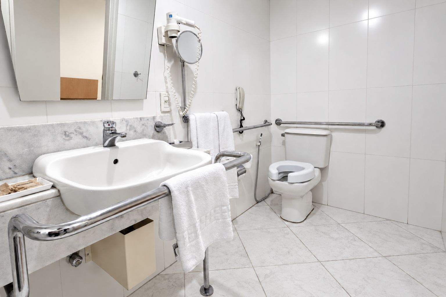 A modern bathroom with a white sink, mirror, and toilet.