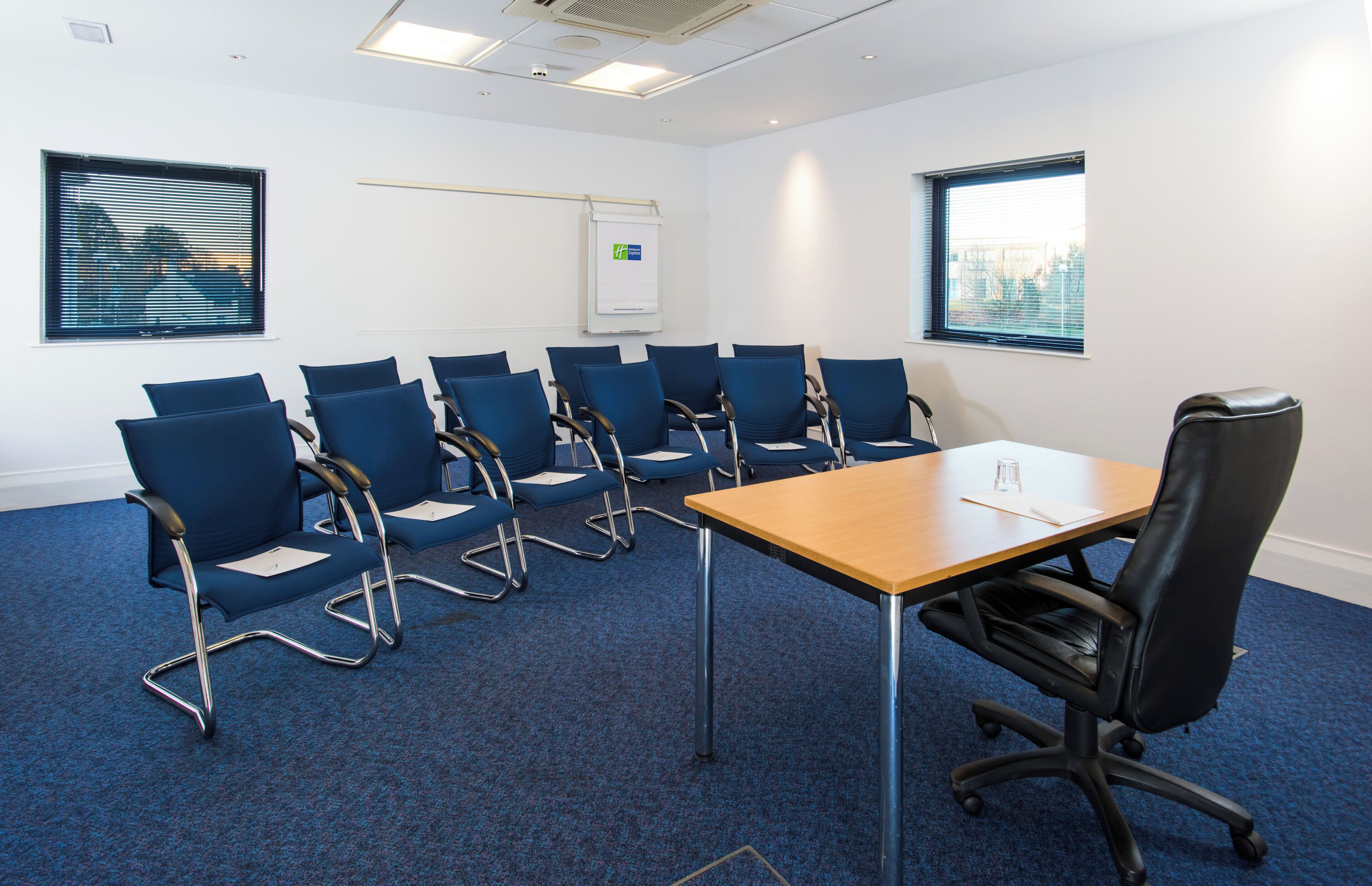 A conference room with a long table and multiple blue chairs.