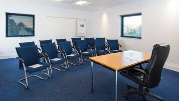 A conference room with a long table and multiple blue chairs.