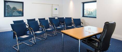 A conference room with a long table and multiple blue chairs.