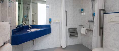 Ein modernes Badezimmer mit einem blauen Waschbecken, einer Toilette, einer Dusche inklusive Handbrause und einem großen Spiegel.