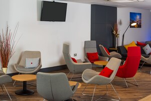 A modern lounge area with multiple seating options, including chairs and sofas, arranged around a central table.