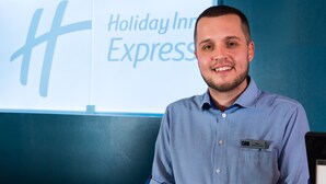 A man in a blue checkered shirt standing in front of a sign that reads "Holiday Inn Express." - Holiday Inn Express Newport by IHG (Newport)