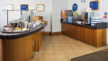Een ontbijtbalk met verschillende soorten eten en een koffieapparaat.
