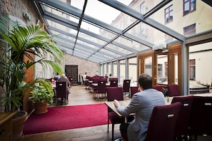 A restaurant with a glass ceiling, red carpet, and wooden tables.
