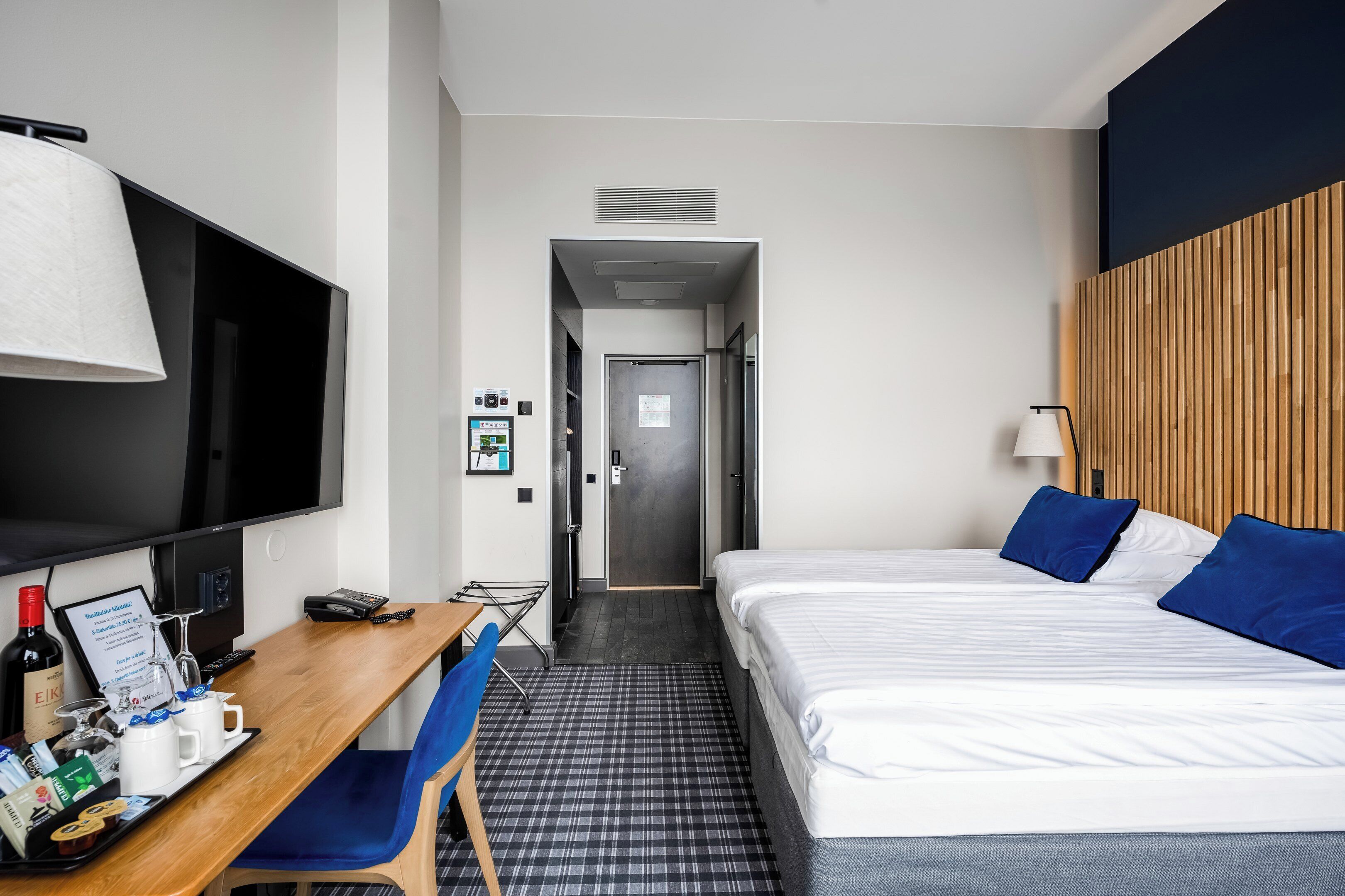 Habitació d'hotel amb llit, escriptori amb ordinador, televisió i cadira.