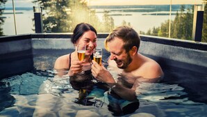 A couple in a hot tub with a view of a lake and trees. - Break Sokos Hotel Koli (Lieksa)