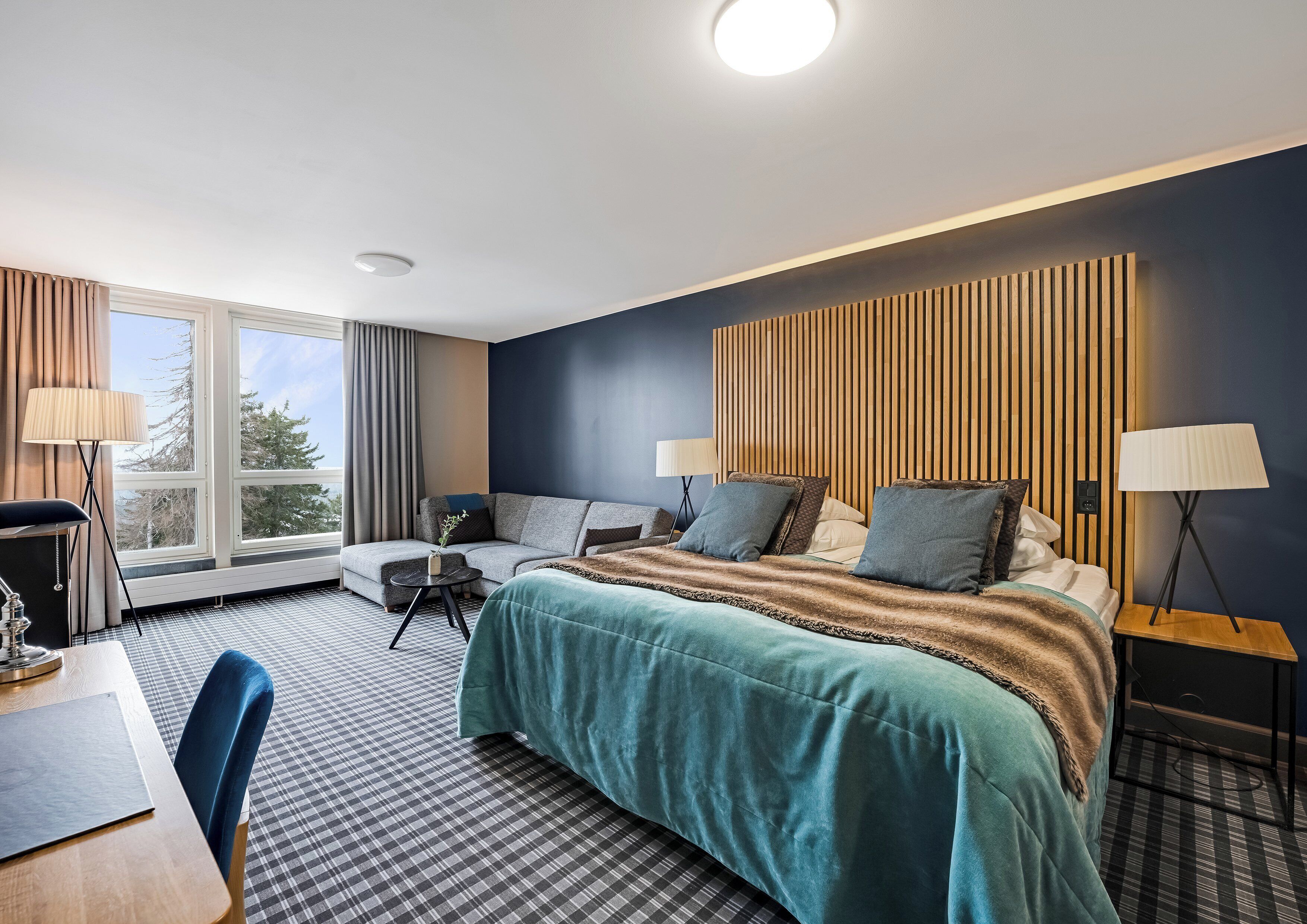 Ein modernes Hotelzimmer mit einem großen Bett, einem Schreibtisch und einer Sitzecke.