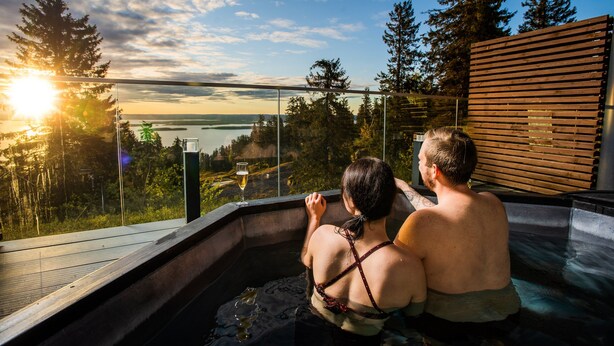 A couple in a hot tub overlooking a scenic view of a lake and forest. - Break Sokos Hotel Koli (Lieksa)