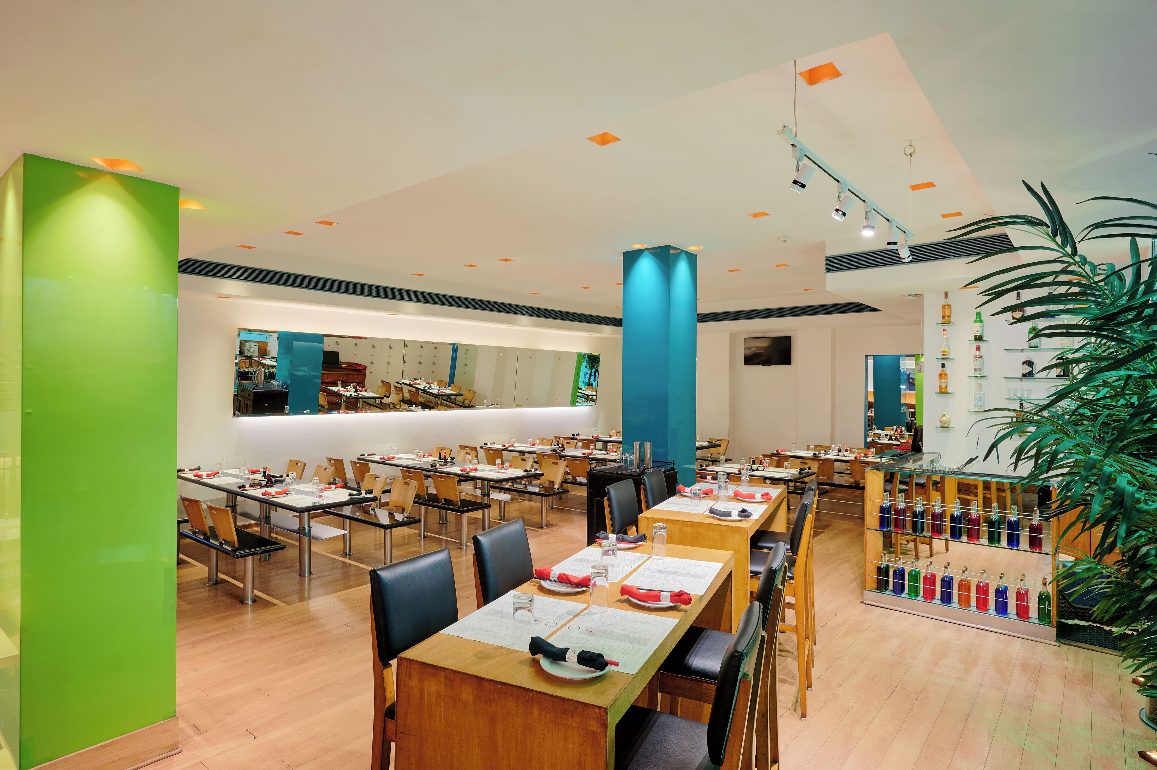 Un comedor amplio con varias mesas y sillas, una zona de bar central y diversas opciones de asientos.