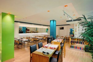Un comedor amplio con varias mesas y sillas, una zona de bar central y diversas opciones de asientos.