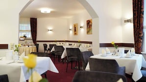 A restaurant with tables set for dining, a chandelier, and artwork on the walls. - Haus Sparkuhl Hotel Garni (Hannover)