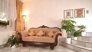 A living room with a wooden sofa, a floor lamp, and potted plants. - Haus Sparkuhl Hotel Garni (Hannover)