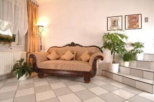 Una sala de estar con un sofá de madera, una lámpara de pie y plantas en macetas.