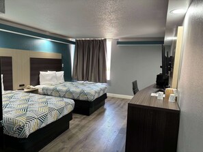 Une chambre d’hôtel avec deux lits, un bureau, une chaise et un grand miroir.