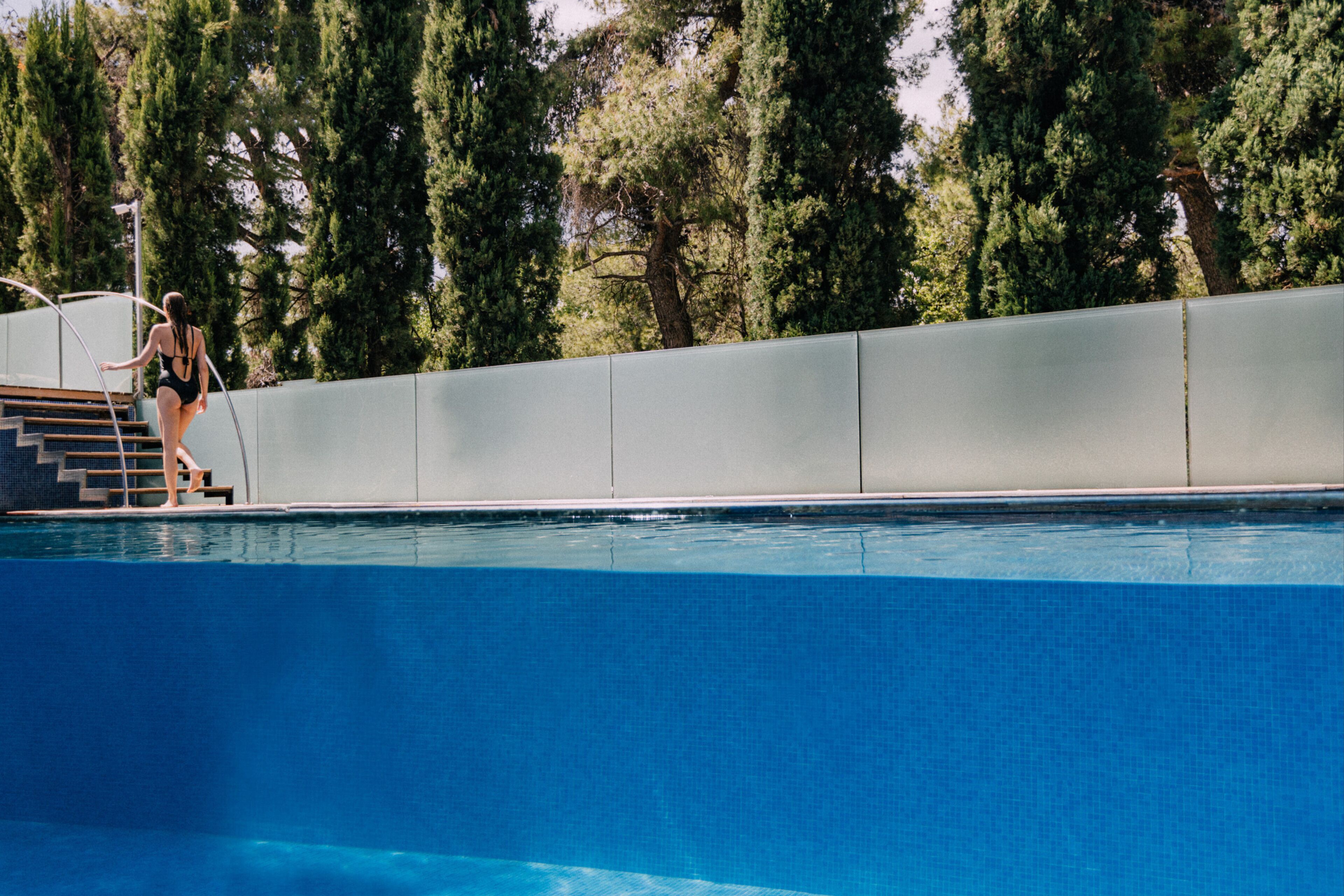 A swimming pool with a diving board and steps leading into the water.