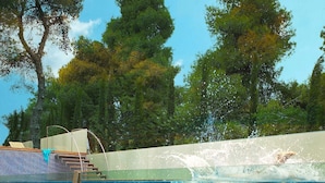 Une piscine à l’eau d’un bleu cristallin, avec un plongeoir et des marches permettant d’y descendre.