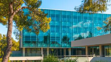 A modern building with a glass facade, surrounded by trees and greenery.