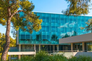 A modern building with a glass facade, surrounded by trees and greenery.