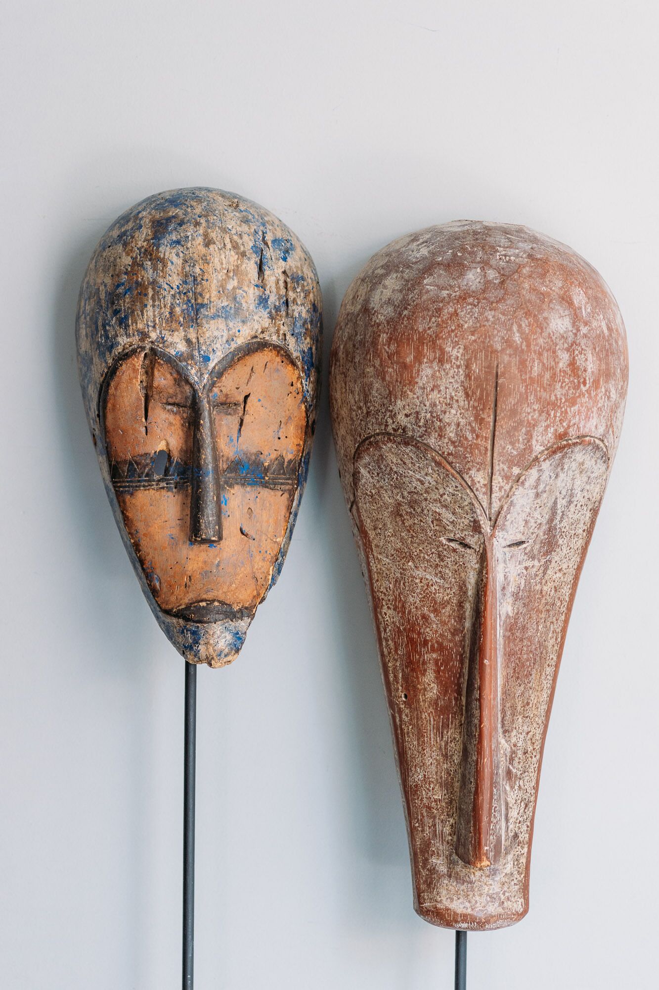 Dos esculturas de madera con rostros tallados, sujetas a postes.