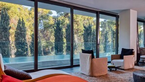 Un salon moderne avec de grandes fenêtres, un canapé, deux fauteuils et une table basse.
