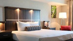 A hotel room with a large bed, two bedside tables, a nightstand, a lamp, and a wall-mounted artwork. - Avi Resort & Casino (Laughlin)