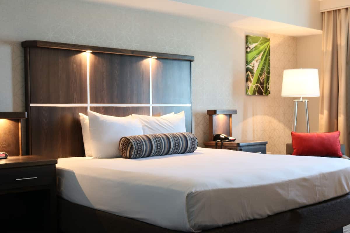 Ein Hotelzimmer mit einem großen Bett, zwei Nachttischen, einer Lampe und einem Wandbild.