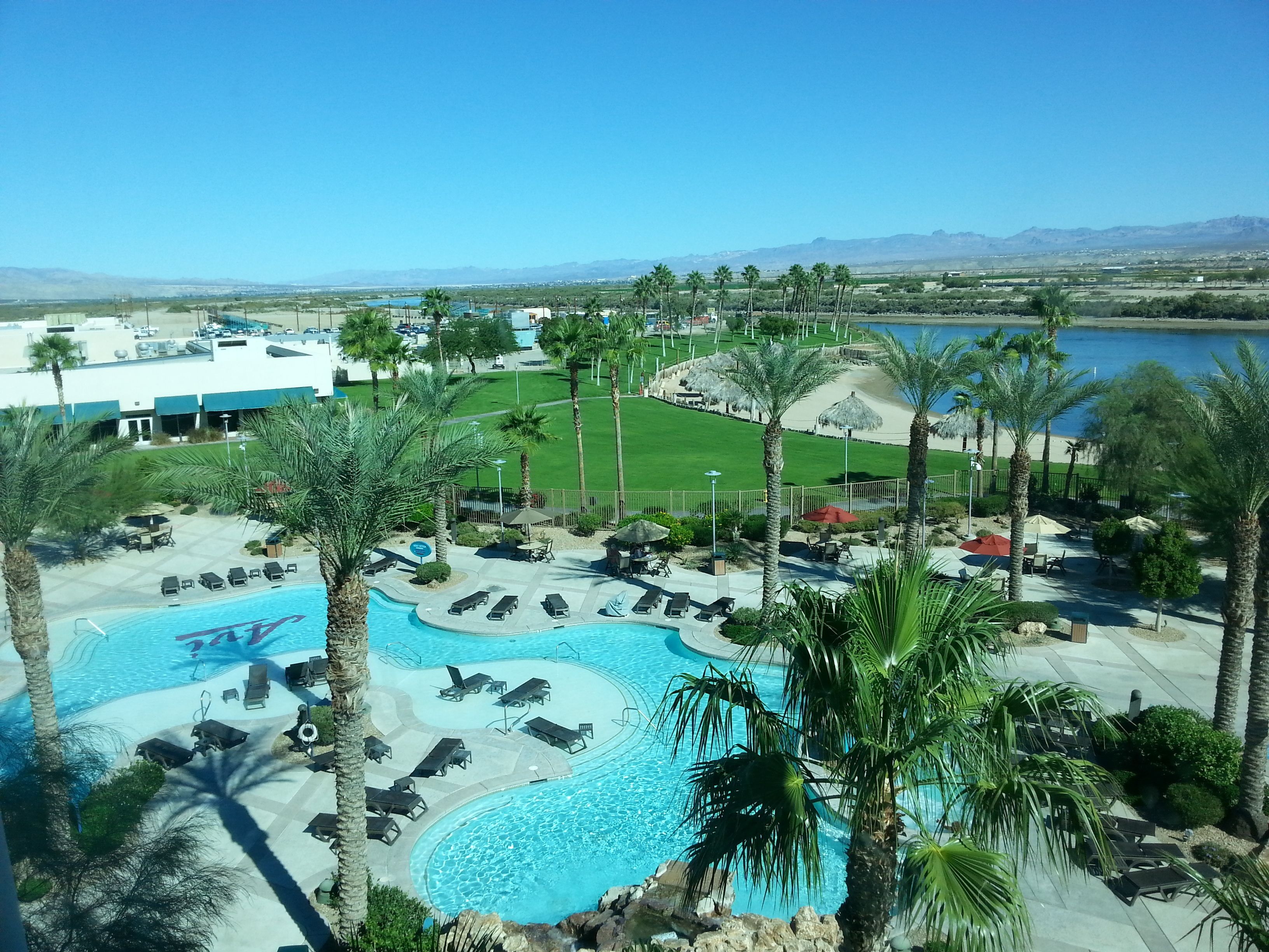 A resort with a large pool, palm trees, and a view of the mountains.