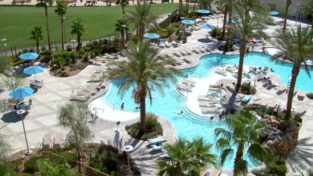 A resort with a large swimming pool, lounge chairs, and palm trees. - Avi Resort & Casino (Laughlin)