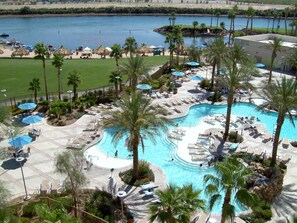 A resort with a large swimming pool, lounge chairs, and palm trees. - Avi Resort & Casino (Laughlin)