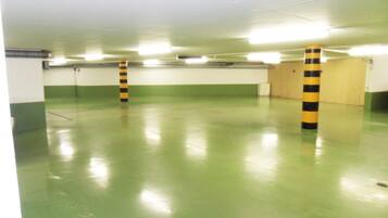 A parking garage with green floors and yellow-striped columns.